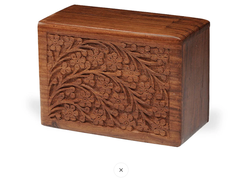 A rectangular wooden keepsake box with a rich medium-brown finish, featuring an intricate hand-carved floral pattern on the front panel, set against a plain white background.